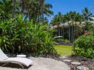 image on a sun deck lounge on a stunning private back yard surrounded by lush garden, featuring pebbles and paved-stepping-stone that leads to the open lawn