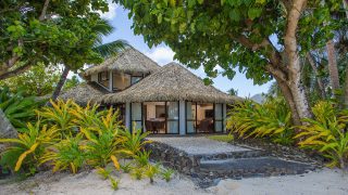 A stunning and luminous view of the Premium Beachfront Villa interior look from the beach showcasing a private garden with a stone-paved-walk way that leads to the beach
