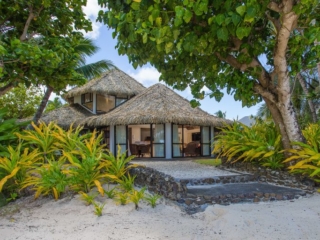A stunning and luminous view of the Premium Beachfront Villa interior look from the beach showcasing a private garden with a stone-paved-walk way that leads to the beach