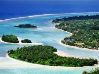 Aerial side-view image of a clear and calm Muri lagoon capturing the forest-covered islets on white sandy beaches with contrasting shades of blue waters of Rarotonga