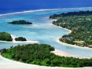 Aerial side-view image of a clear and calm Muri lagoon capturing the forest-covered islets on white sandy beaches with contrasting shades of blue waters of Rarotonga