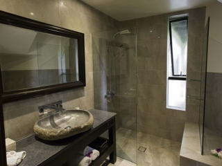 Premium Lagoon View Villa featuring an oval-shaped stone-built bathroom basin overlooking a glass-see-through shower room with water resistant glossy tiles