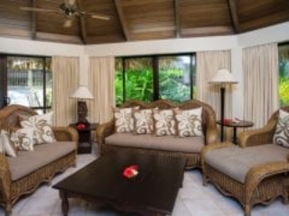 A luminous living room of the Premium Beachfront Villa showcasing the polished brown furniture with contrasting background featuring a tropical lush garden