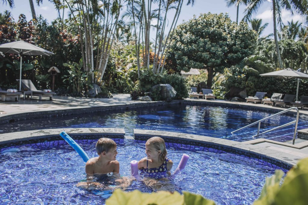 image of children enjoying a bath in the kids pool overlooking a stunning background of the adults pool and a polished green garden surroundings