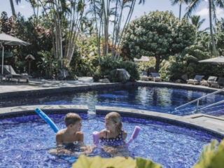 image of children enjoying a bath in the kids pool overlooking a stunning background of the adults pool and a polished green garden surroundings