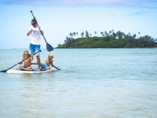 Image of resort guests, father and two sons paddling on a Stand-Up Paddleboard in the Muri Lagoon
