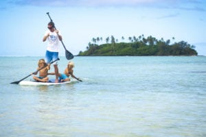 Image of resort guests, father and two sons paddling on a Stand-Up Paddleboard in the Muri Lagoon
