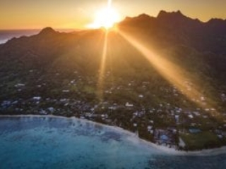 a stunning aerial image of Rarotonga Island capturing a breath-taking sunset that illuminates the turquoise waters of Muri Lagoon