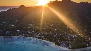 a stunning aerial image of Rarotonga Island capturing a breath-taking sunset that illuminates the turquoise waters of Muri Lagoon