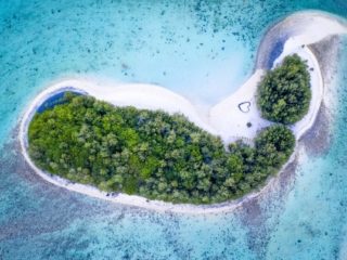 a stunning aerial image of the islets in the Muri lagoon capturing a heart symbol printed on a glowing white sandy beach