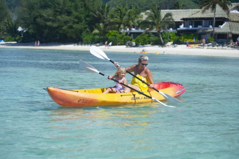 Image of mum enjoy coaching daughter, a toddler, the paddle moves on the paddle-board along the Muri Lagoon