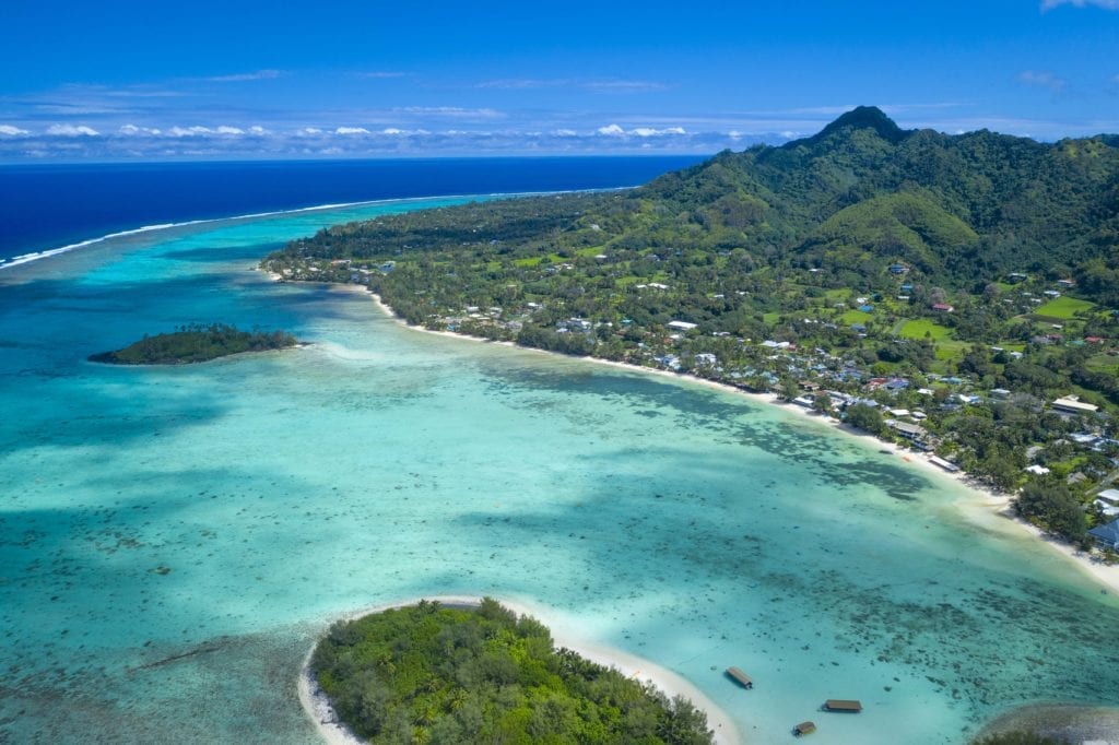 a beautiful aerial image of the South-Eastern side of Rarotonga featuring a forest-covered islets in the Muri lagoon capturing a breathtaking contrasting blue colour of the open waters in the background