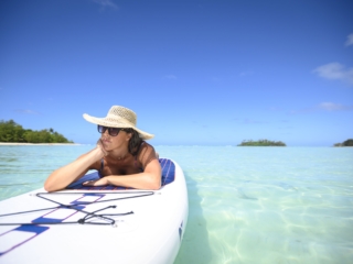 image of a lady sun-tanning on a stand up paddle board afloat in the lagoon