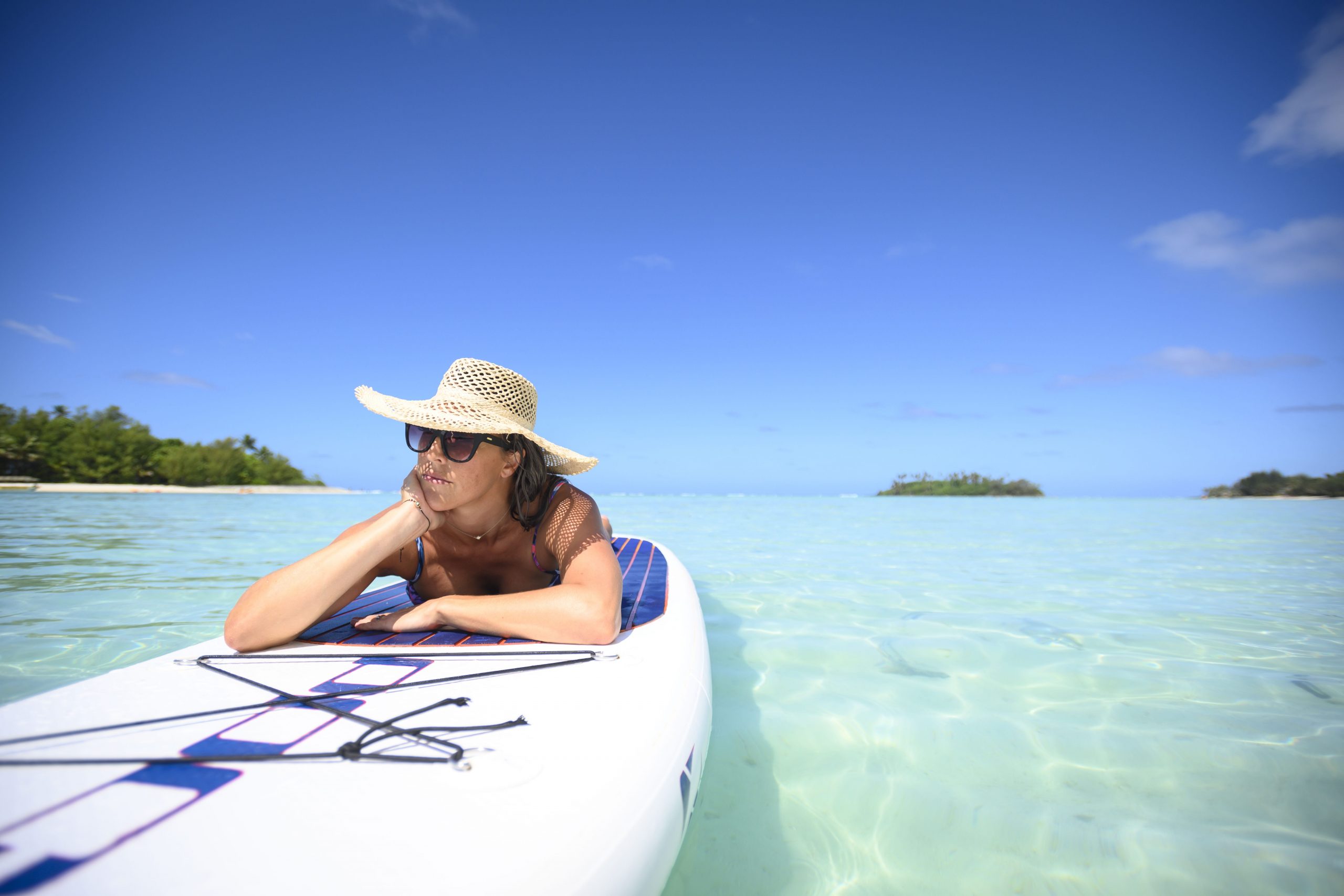 image of a lady sun-tanning on a stand up paddle board afloat in the lagoon