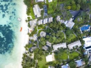 aerial image of Pacific Resort Rarotonga capturing a contrasting yellowish-orange kayaks lined up on a white-sandy beach parallel to the shoreline