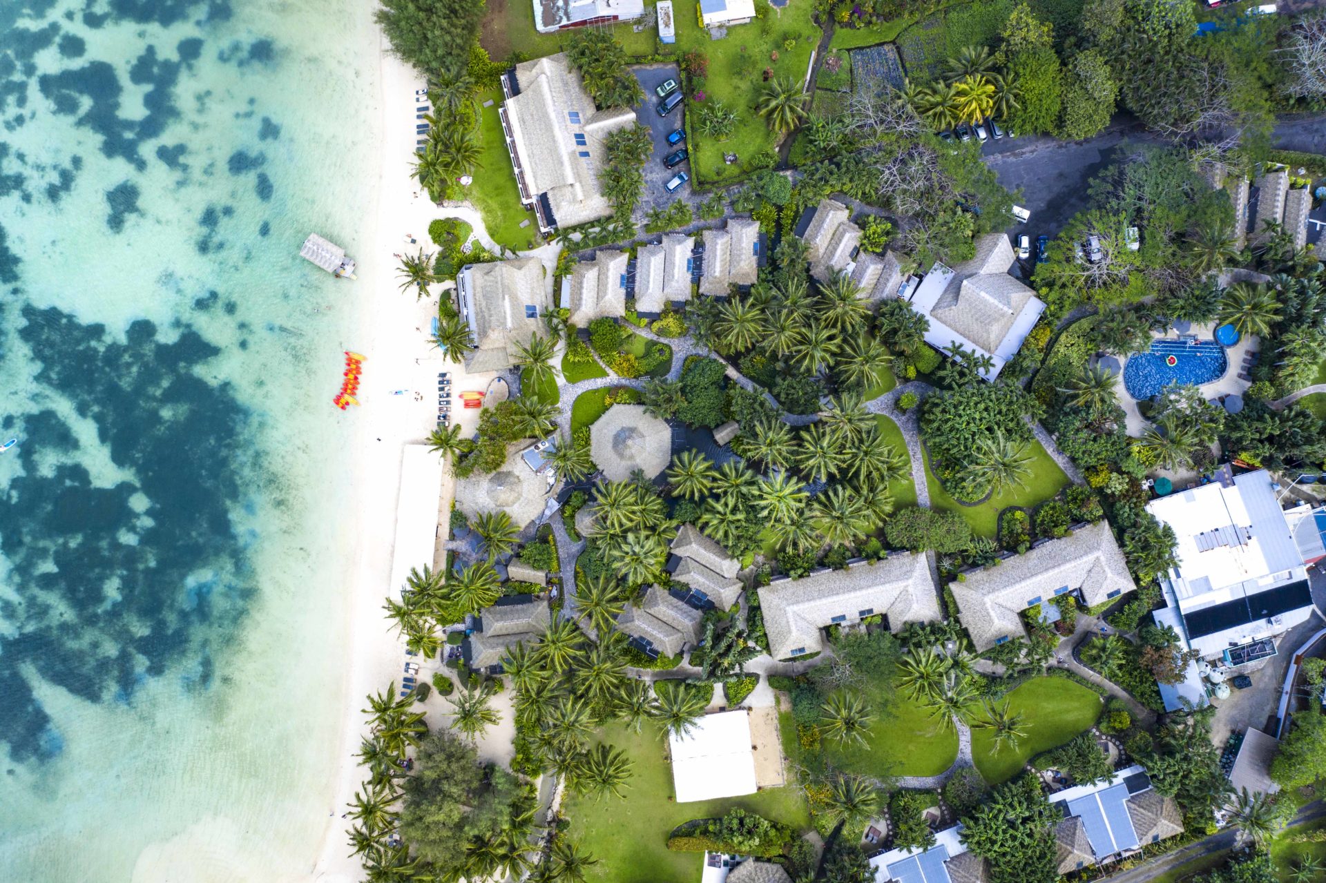 aerial image of Pacific Resort Rarotonga capturing a contrasting yellowish-orange kayaks lined up on a white-sandy beach parallel to the shoreline